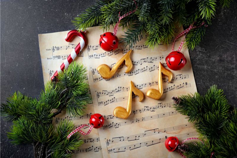 Image of sheet music with red and white candy canes, Christmas tree branches and golden musical notes.